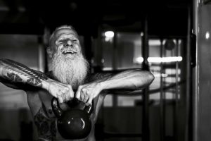 man with grey board working out with kettle bell